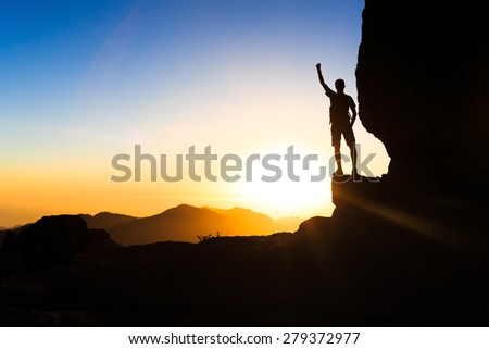 Man climbing hiking exploring accomplish silhouette in mountains, sunset and ocean. Male hiker with backpack on top of mountain looking at beautiful night landscape.