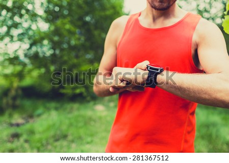 Runner on mountain trail checking looking at sportwatch smart watch, cross country runner checking performance, GPS position or heart rate pulse. Sport smartwatch and fitness equipment on summer trail