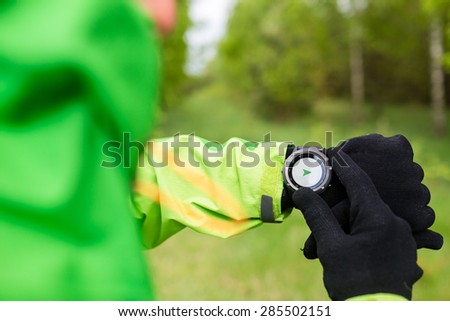 Hiker looking at electronic compass, sport gps smart watch. Man checking direction on smartwatch, navigation equipment. Hiking healthy sport and fitness outdoors in nature.