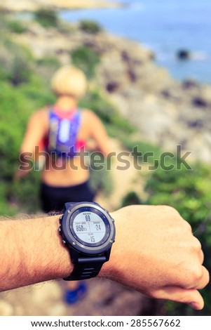 Runner or hiker on mountain trail looking at sports watch, healthy lifestyle. Checking GPS position, performance or heart rate pulse and training working out. Sport and fitness outdoors in nature.