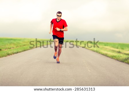 Man running on country road, healthy fitness lifestyle, sport speed training beautiful landscape. Young runner jogging training and doing workout exercising power walking outdoors in nature.