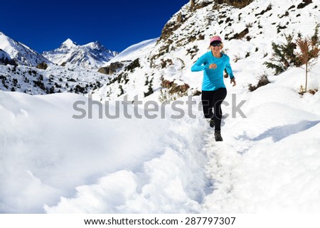 Happy woman cross country trail running in beautiful inspiring mountains landscape. Healthy lifestyle, fitness and exercising outdoors in winter nature. Inspiration and motivation fit and be healthy.