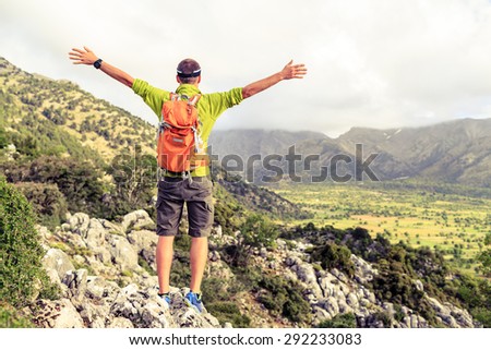 Happy climber hiker winning reaching life goal, success man at summit, successful business concept. Young runner hiker arms up outstretched,freedom and happiness rock climbing achievement in mountains