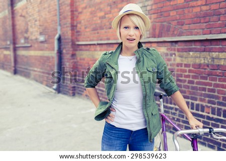 Hipster cyclist young beautiful girl with vintage road bike on city street, urban scene. Commuting to work concept. Woman cycling on fixed gear bike in town, retro city street industrial background.