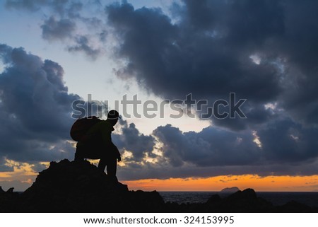 Man hiker sitting accomplish silhouette backpacker, looking at inspirational ocean island landscape, freedom concept. Fitness and healthy lifestyle outdoors at beach Crete, Greece.
