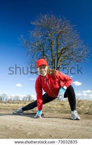 Woman stretching  and exercising on dirt country road. Running and healthy lifestyle concept. Happy female runner on outdoors exercising workout in nature.