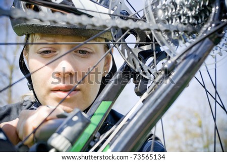 Young woman repairing bicycle during bike trip