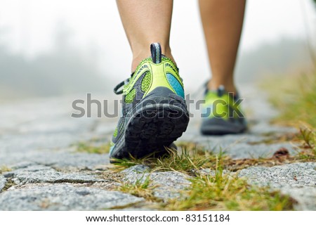 Woman walking in mountains in sport hiking shoes. Jogging or training outside in summer nature, motivational health and fitness concept.