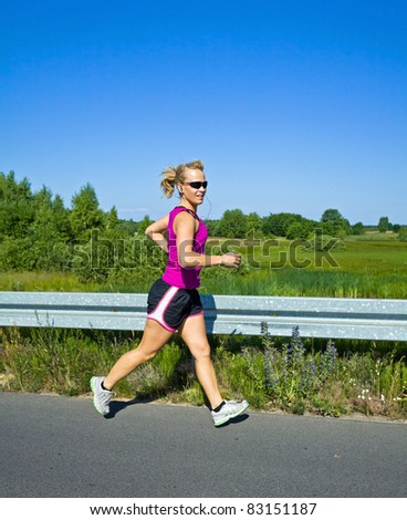 Happy woman running on country road in sunny summer