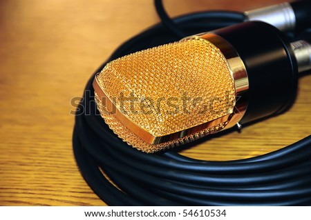 Studio gold microphone on dark wooden background