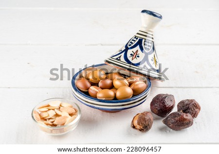 Argan Fruit on a wooden tabletop, Some fruit are without shell, other are in a Moroccan Tajine