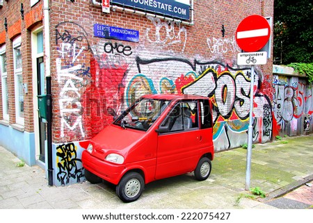 AMSTERDAM, NETHERLANDS - AUGUST 10, 2014: Tiny car Canta LX at the city street near the graffiti wall and the bicycle only sign.