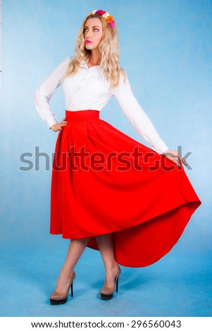 Beautiful young woman in a long red skirt over cyan background