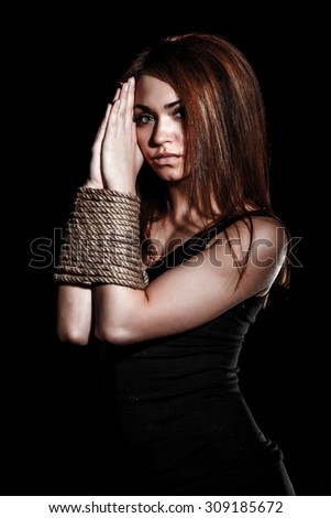 Beautiful young woman with tied arms over black background