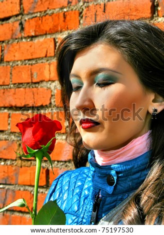 Girl with a red rose near a brick wall