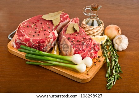 raw meat with rosemary, onion, garlic, peppercorn, lemon and oil