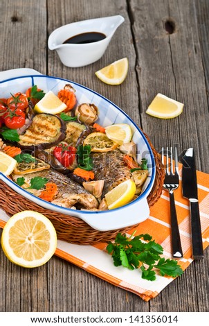 seabass fish baked with vegetables, herbs and lemon on a dish