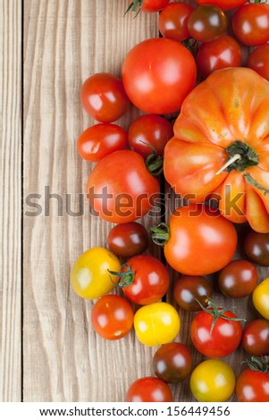 Border made from yellow, red and black tomatoes on wooden background