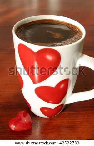 Cap of coffee with hearts and a little heart on a table