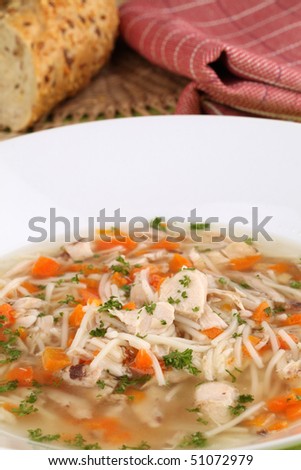 Chicken soup with pieces of meat, carrot, noodles and parsley
