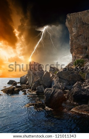 Dramatic nature background - rocks, sea, dark sky with lightning