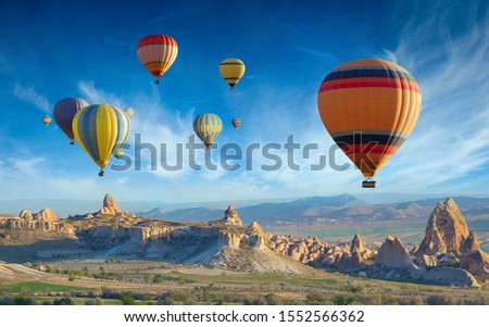 Surise view of unusual rocky landscape in Cappadocia, Turkey. Colorful hot air balloons fly in blue sky over amazing valleys with fairy chimneys in Cappadocia.