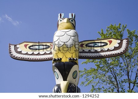 Top of totem pole against blue sky.