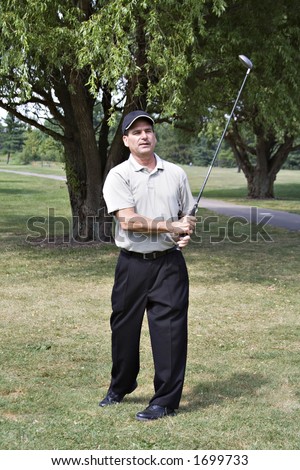 Man with satisfied expression views his golf drive.