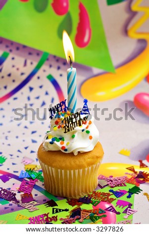 Birthday Party Cupcake with bright colorful background.  Blue lit candle sprinkles and confetti.