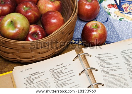 A recipe book turned to apple pie recipe - basket of apples.