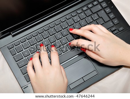 Close-up of female fingers typing a document on the black laptop