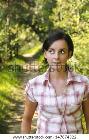A young Caucasian girl looking surprised wearing mountain clothes on a hiking path in the wood