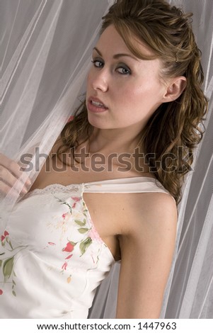 Beautiful young woman posing with white netting in studio setting Beautiful young woman posing with white netting