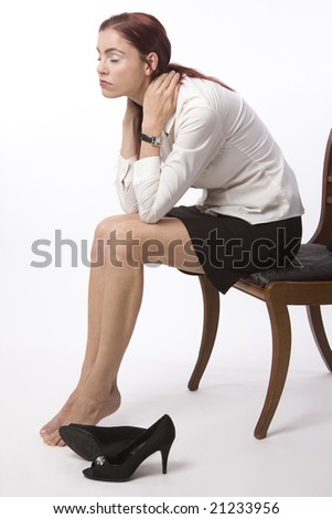 Woman in business attire sitting with her shoes off, looking exhausted