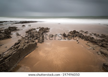 Long exposure landscape beach scene with moody sky