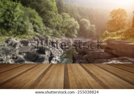 Beautiful morning landscape image of sunlight through trees into canyon creek below with wooden planks floor