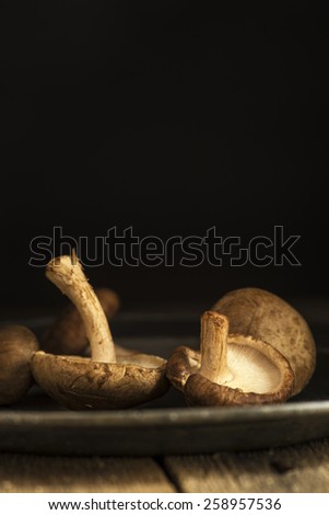 Fresh shiitake mushrooms in moody natural light setting with vintage style