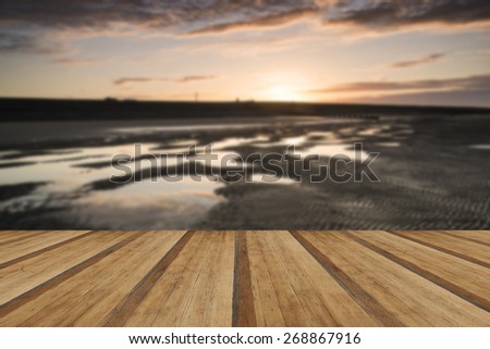 Beautiful sunrise reflected in low tide water pools on beach landscape with wooden planks floor