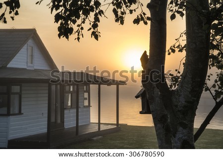 Beautiful sunrise glow over foggy river house in countryside landscape