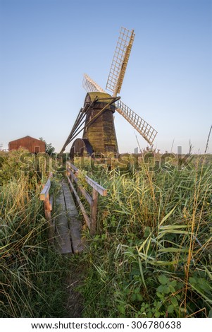 Old drainage pump windmill in English countryside landscape