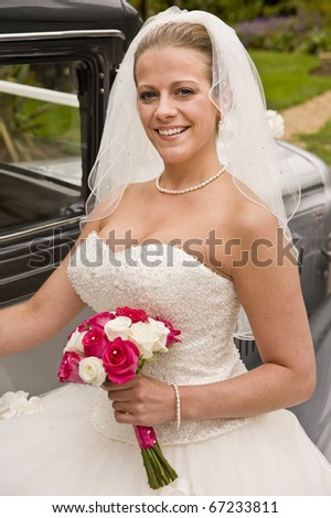 Portrait of beautiful young bride entering vintage wedding car