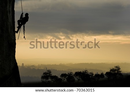 Silhouette of single rock climber against stunning sunset concept of achievement