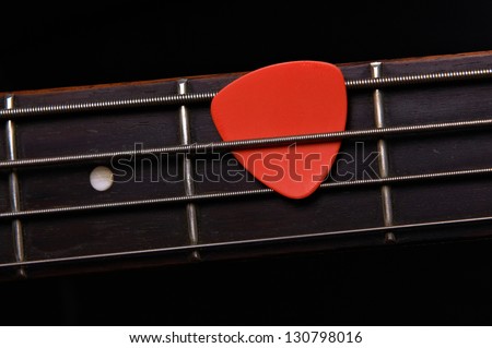 Orange guitar pick on the fingerboard