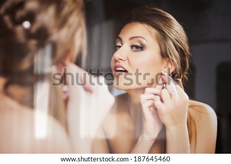 Young attractive bride putting on a earring
