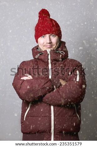 Handsome man wearing red scarf, red woolen hat. Covered with snow. Cold. Casual look.