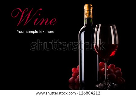 bottle of red wine, glass and grapes on dark background with place for text