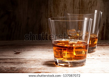two glasses of whiskey over wooden background