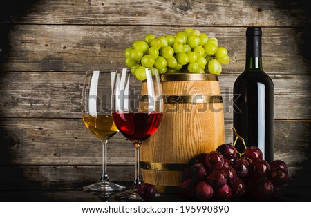 two glasses of wine with fresh fresh grapes, bottle and barrel in front of old grunge wooden planks