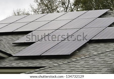 Array of solar panels on sloped roof of detached house on an overcast morning