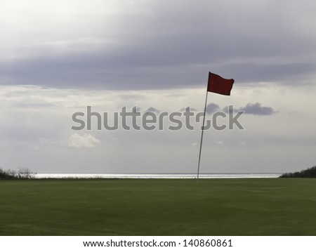 Silhouette of flag flapping on golf green near Atlantic Ocean on an overcast morning, North Truro, Massachusetts (emblem of Highland Links, owned by U.S. federal government, removed from the flag)